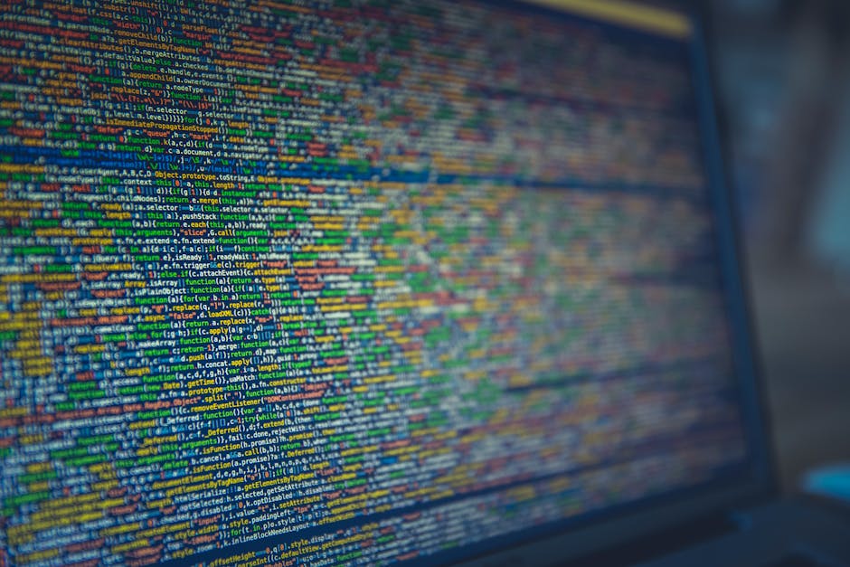 A close-up view of a computer screen displaying multicolored lines of programming code in a text editor, with visible syntax highlighting and text formatting. The screen shows a dense arrangement of c